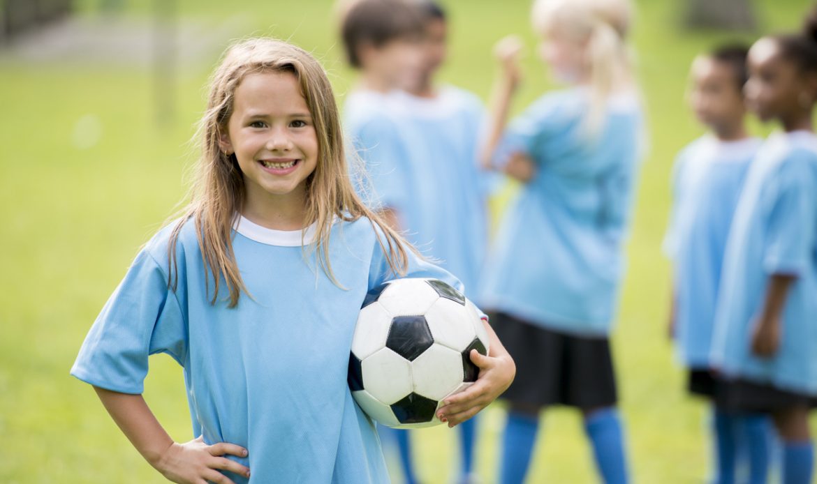 Little kids playing soccer outside.